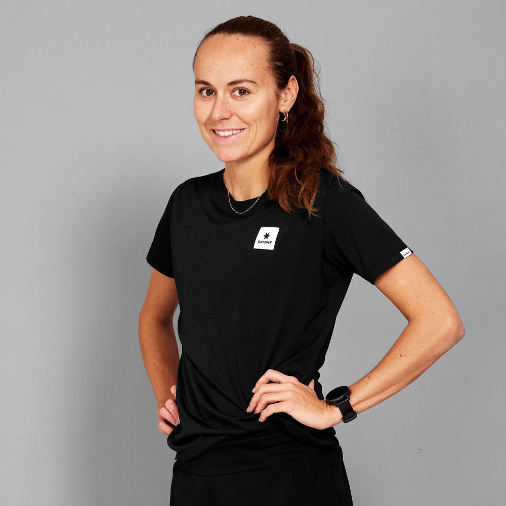 Woman wearing a black t-shirt with a logo on a gray background