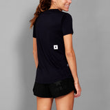 Woman wearing a black athletic outfit with a logo on a gray background