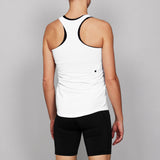 Person wearing a white tank top with black trim and black shorts on a gray background