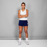 Woman wearing a white tank top and blue shorts with a logo on a gray background