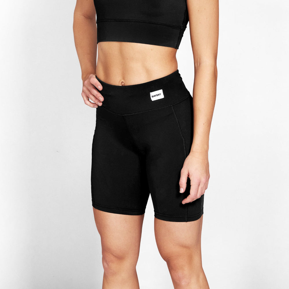 Person wearing black athletic shorts with a visible brand logo on a light gray background