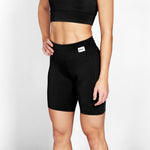 Person wearing black athletic shorts with a visible brand logo on a light gray background