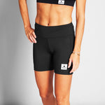 Person wearing black athletic shorts with a visible brand logo on a gray background