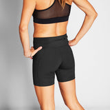 Person wearing black athletic shorts and sports bra on a gray background
