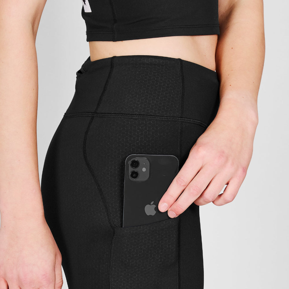 Person wearing black leggings with a phone pocket, holding a black phone.